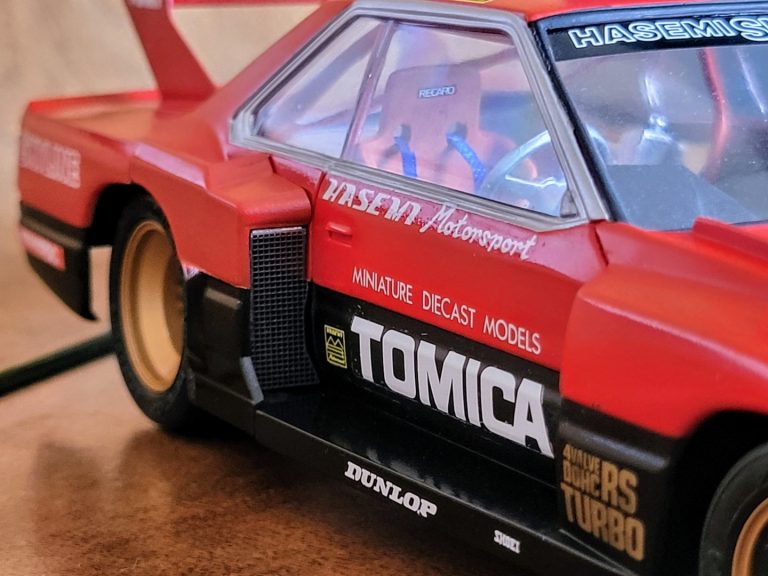 Close-up of a red TOMICA racing car model showing details and branding.