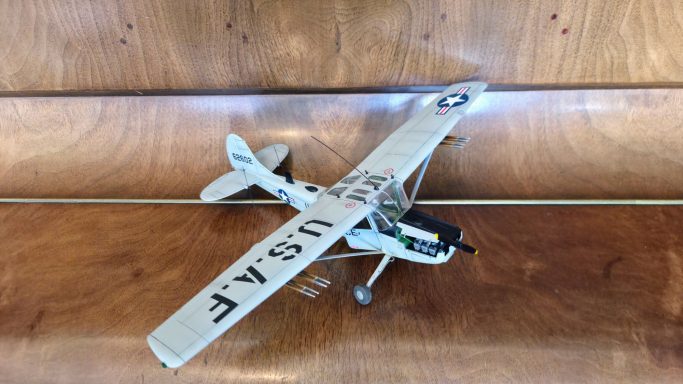 Model aeroplane with a pale body and black details on a wooden surface.
