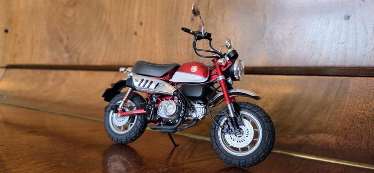 Model of a red and white motorcycle displayed on a wooden surface.
